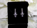 "J" hoop .25ct natural diamond earrings channel set in 10K white gold on a black pad with a white floral background.