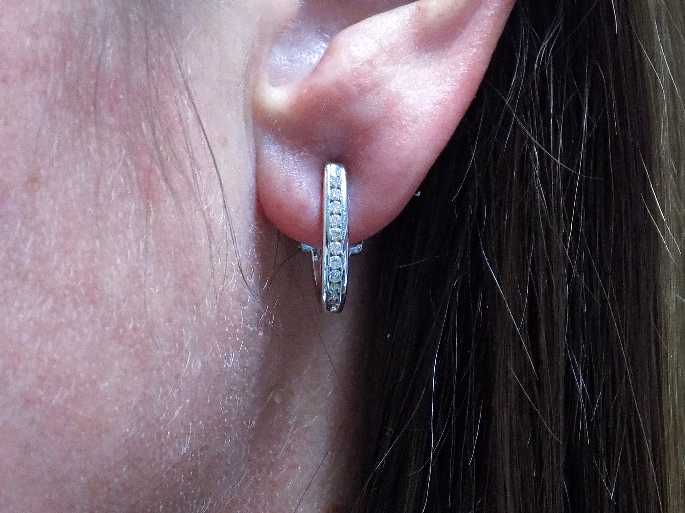 "J" hoop .25ct natural diamond earrings channel set in 10K white gold in a ladies ear.