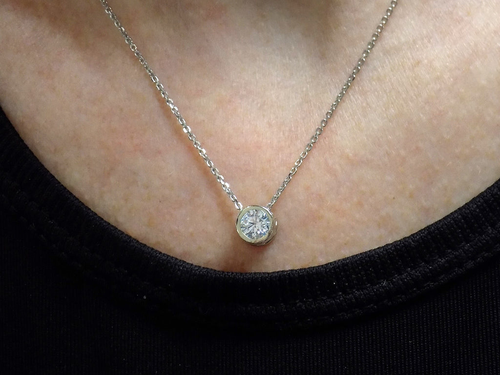 This is a bezel set slide .40ct natural diamond necklace in 14K white gold on a ladies neck.