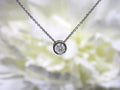This is a bezel set slide .40ct natural diamond necklace in 14K white gold with a white floral background.