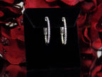This is .50ct total weight natural diamond inside out hoop earrings in 10K white gold on a black pad with a red floral background.