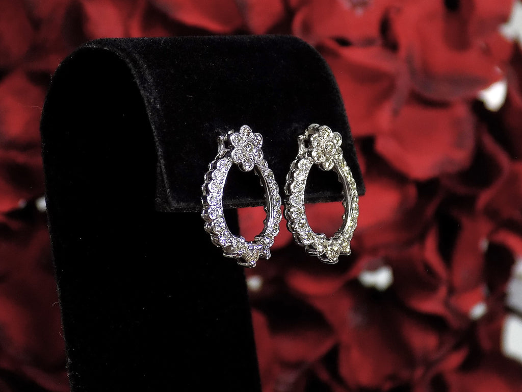 This is Victorian style natural diamond dangle post style earrings with 1.00ct total weight in diamonds set in 14K white gold on a black pad with a red floral background in a side view.