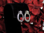 This is Victorian style natural diamond dangle post style earrings with 1.00ct total weight in diamonds set in 14K white gold on a black pad with a red floral background in a side view.