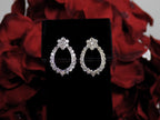 This is Victorian style natural diamond dangle post style earrings with 1.00ct total weight in diamonds set in 14K white gold on a black pad with a red floral background.