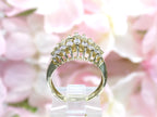 This is a vintage 2-row natural diamond ring with 1.00ct total weight of diamonds in 14K yellow gold side view on a mirrored surface with a pink floral background.