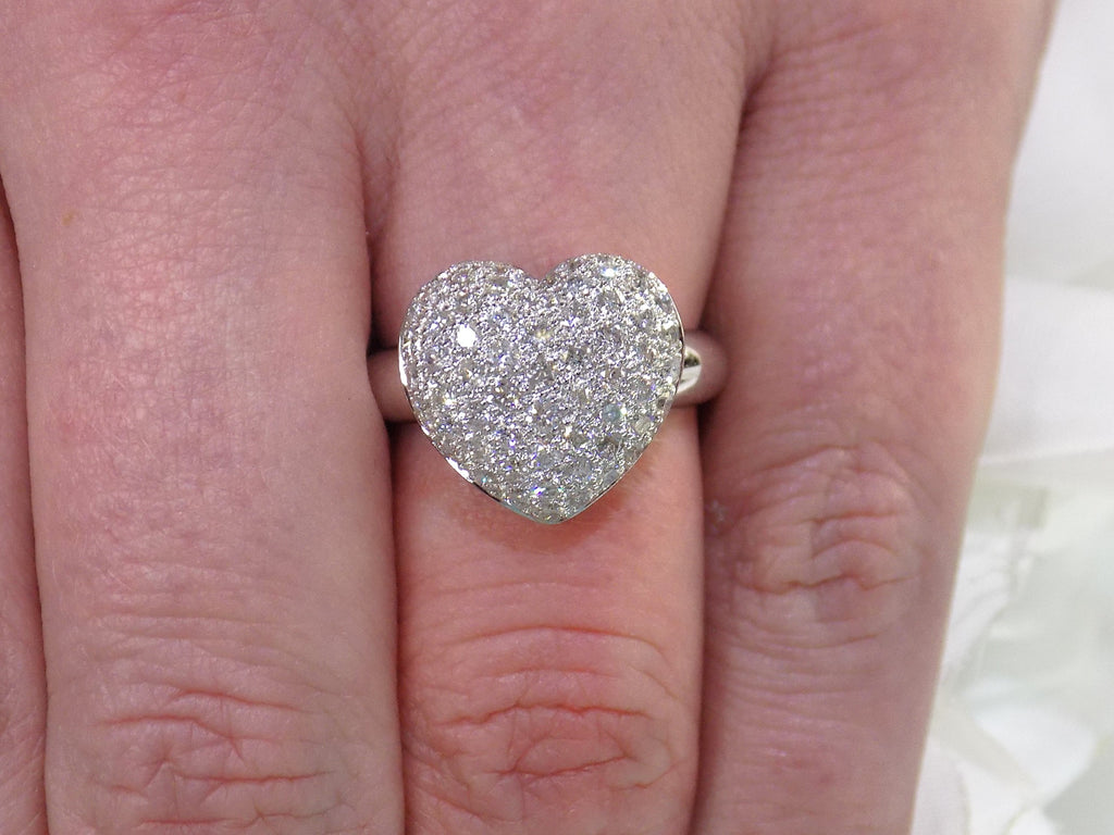 This is a 1.00ct heart shaped pave set natural diamond ring in 18K white gold on a ladies finger.