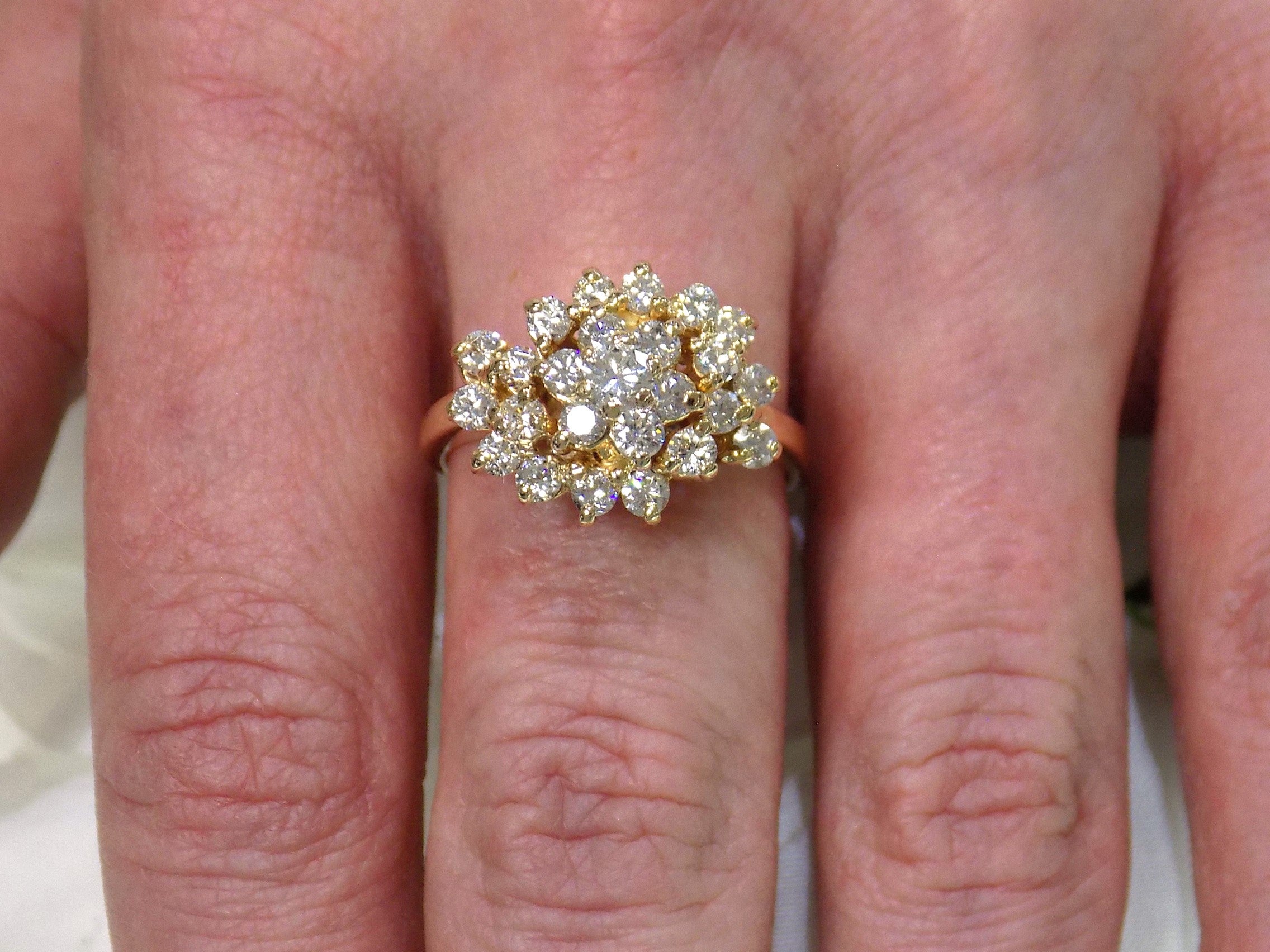 This is 1.20ct total weight natural diamond cluster cocktail ring in 14K yellow gold on a ladies finger.