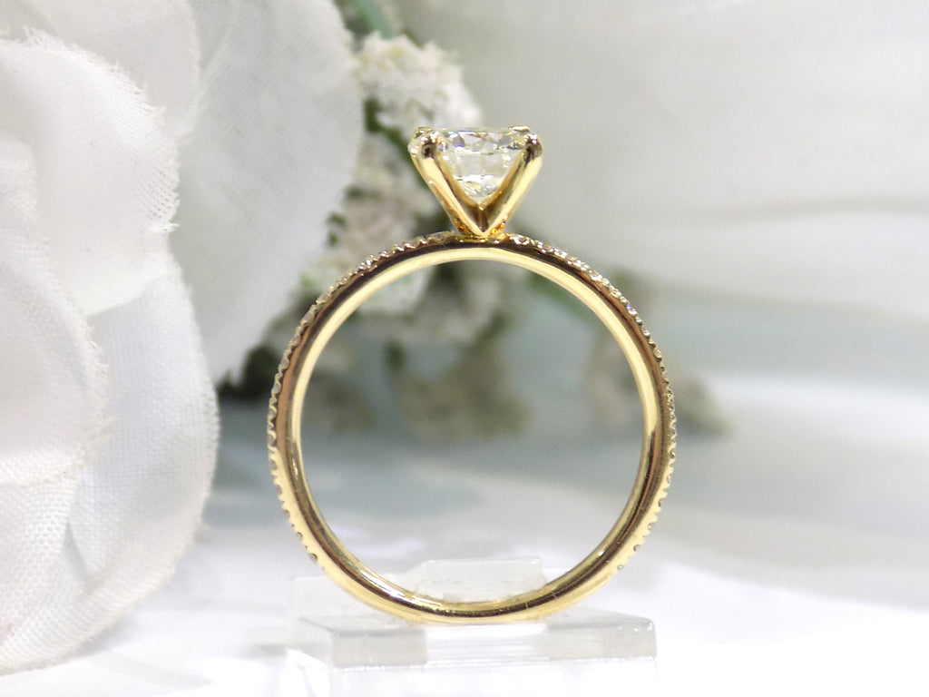 This is a side view of a women's natural round brilliant diamond ring with a 1.02ct center and .23ct in accents diamonds set in yellow gold shown with white background.