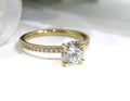 This is a women's natural round brilliant diamond ring with a 1.02ct center and .23ct in accents diamonds set in yellow gold shown with white background.
