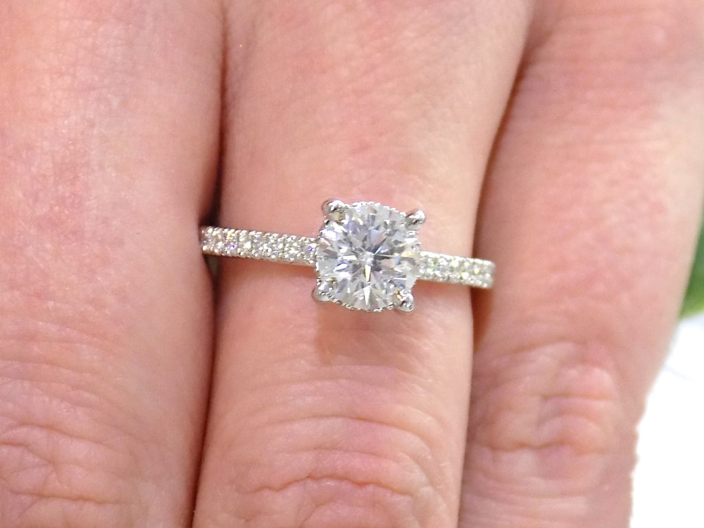 This is a straight line style 1.39ct total weight natural round brilliant diamond ring in white gold shown on a woman's finger.