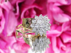 This is a women's 1.50ct total weight women's natural diamond 2-piece wedding set with the engagement ring and matching diamond band in yellow gold shown with a mirrored flowery background.