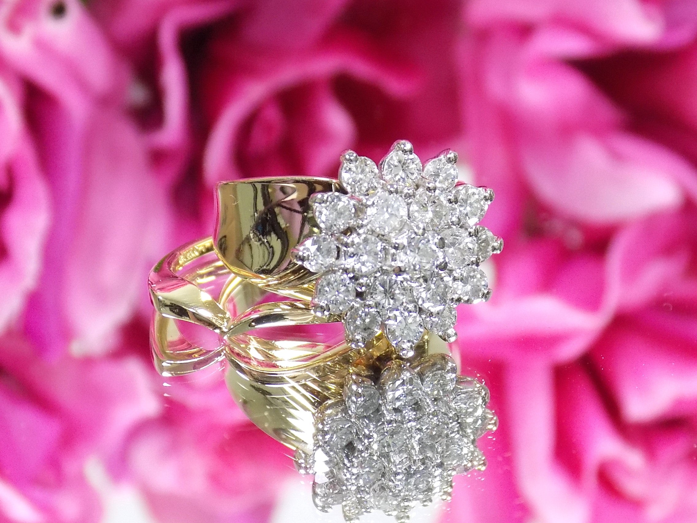 This is a women's 1.50ct total weight women's natural diamond 2-piece wedding set with the engagement ring and matching diamond band in yellow gold shown with a mirrored flowery background.