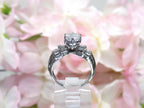 This is a side view of 1.50ct total weight natural diamond ring in white gold from our estate collection shown with a pink floral background.