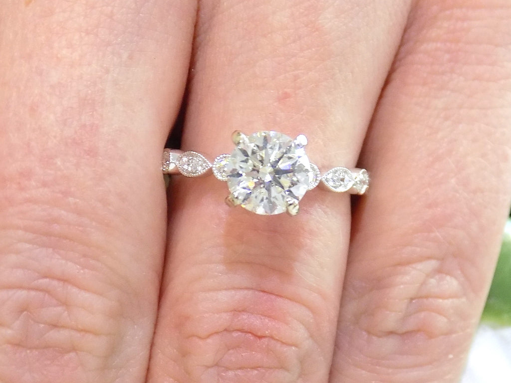 This is a women's 1.72ct total weight natural round diamond engagement ring in white gold shown on a woman's finger.
