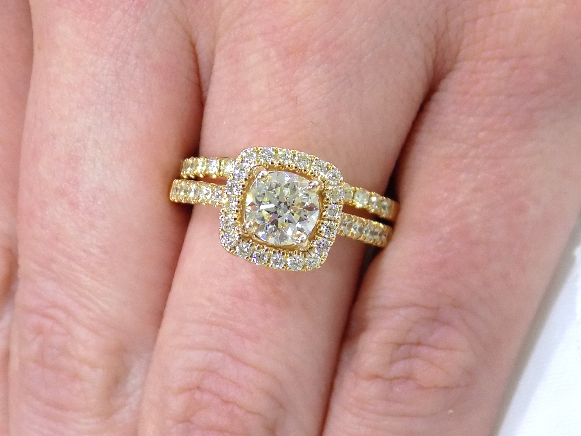 This is a halo style 2-piece wedding set which includes the engagement ring and a matching band for a total of 1.77ct in natural round diamonds shown on a woman's finger.