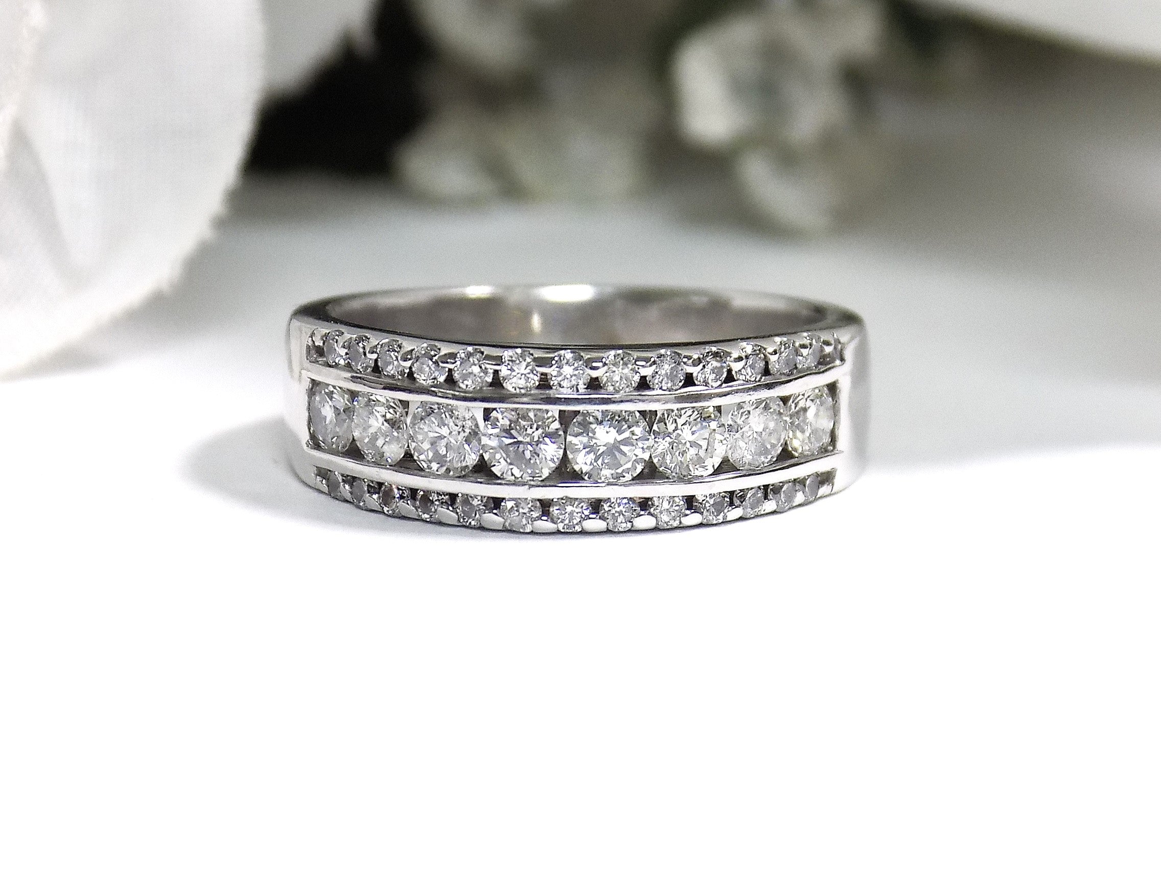 This is 3-row channel & prong set 1.00ct total weight natural wide diamond band in white gold with a white background. 
