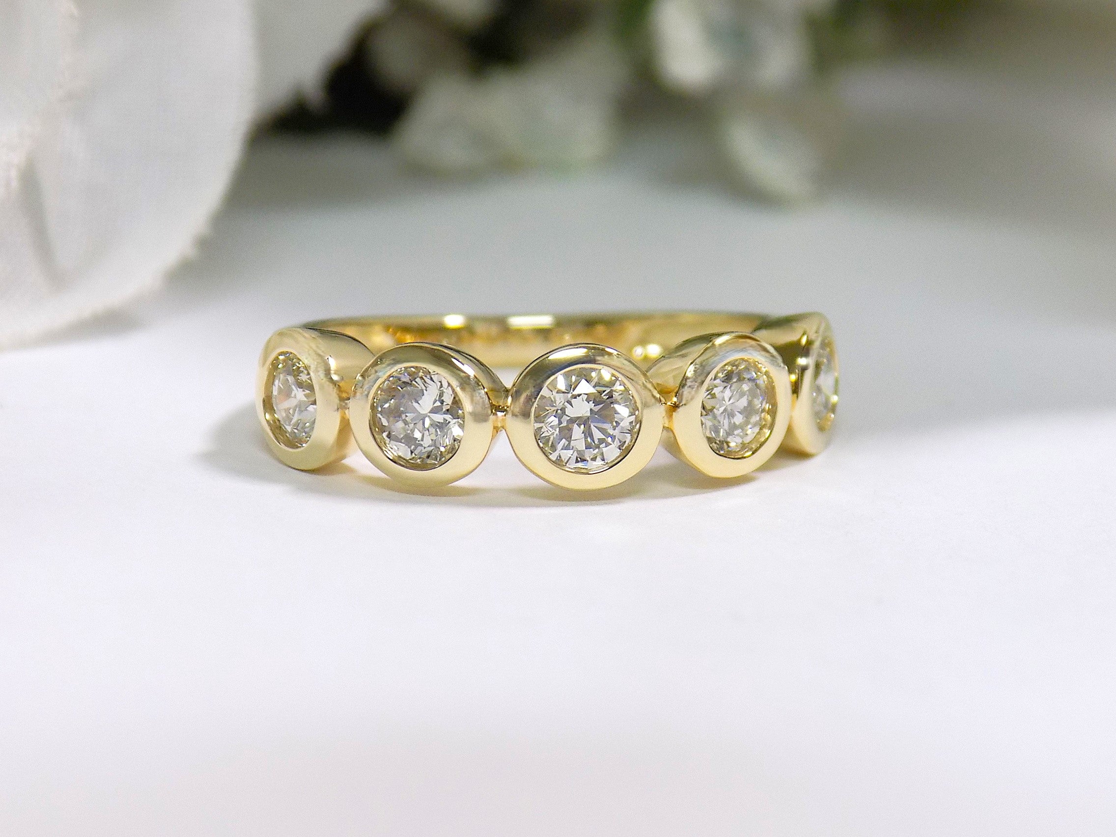 This is a bezel set 5-stone natural 1ct total weight diamond band in yellow gold with a white background.