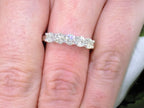 This is a 5-Stone natural diamond band in white gold shown on a woman's finger.