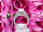 This is a side view of a 1.00ct total weight natural diamond ring in white gold shown with a pink floral background.