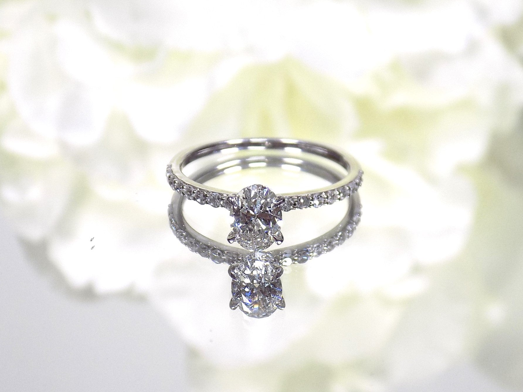 This a 1ct total weight natural oval shape diamond set on a straight line diamond band in white gold.