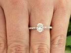 This a 1ct total weight natural oval shape diamond set on a straight line diamond band in white gold shown on a woman's finger.