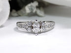 This is a marquise shape diamond ring with round diamond accents in white gold with a white background.