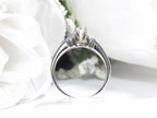 This is a marquise shape diamond ring with round diamond accents in white gold shown from the side with white background.