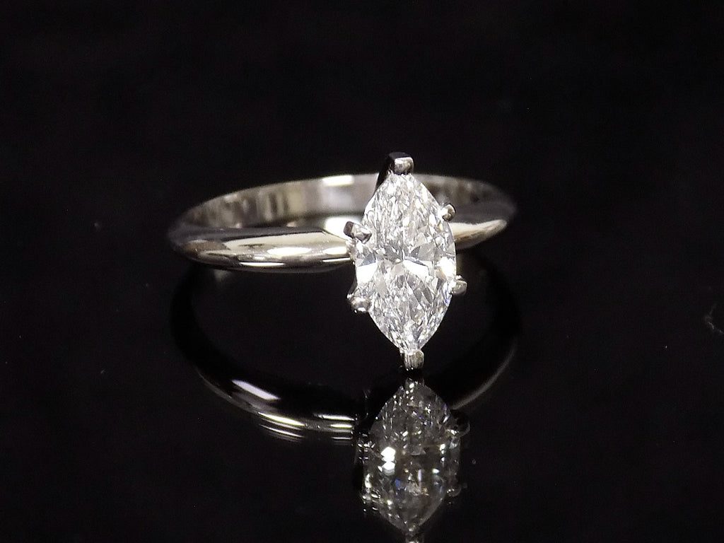 This is a 1ct marquise shape diamond solitaire ring in white gold on black mirrored background.
