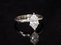 This is a 1ct marquise shape diamond solitaire ring in white gold on black mirrored background.