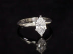 This is a 1ct marquise shape diamond solitaire ring in white gold on black mirrored background.