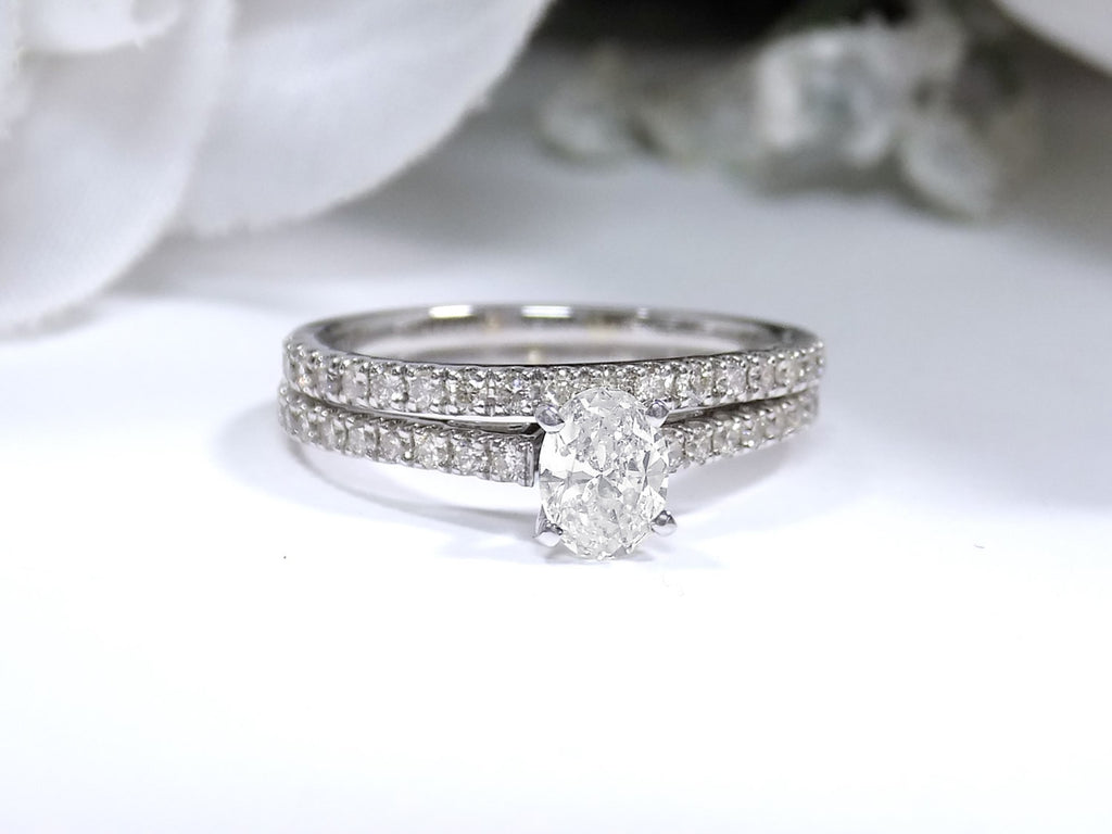 This is a natural 1ct total weight oval shape diamond bridal set with engagement ring and matching band in white gold with a white background.