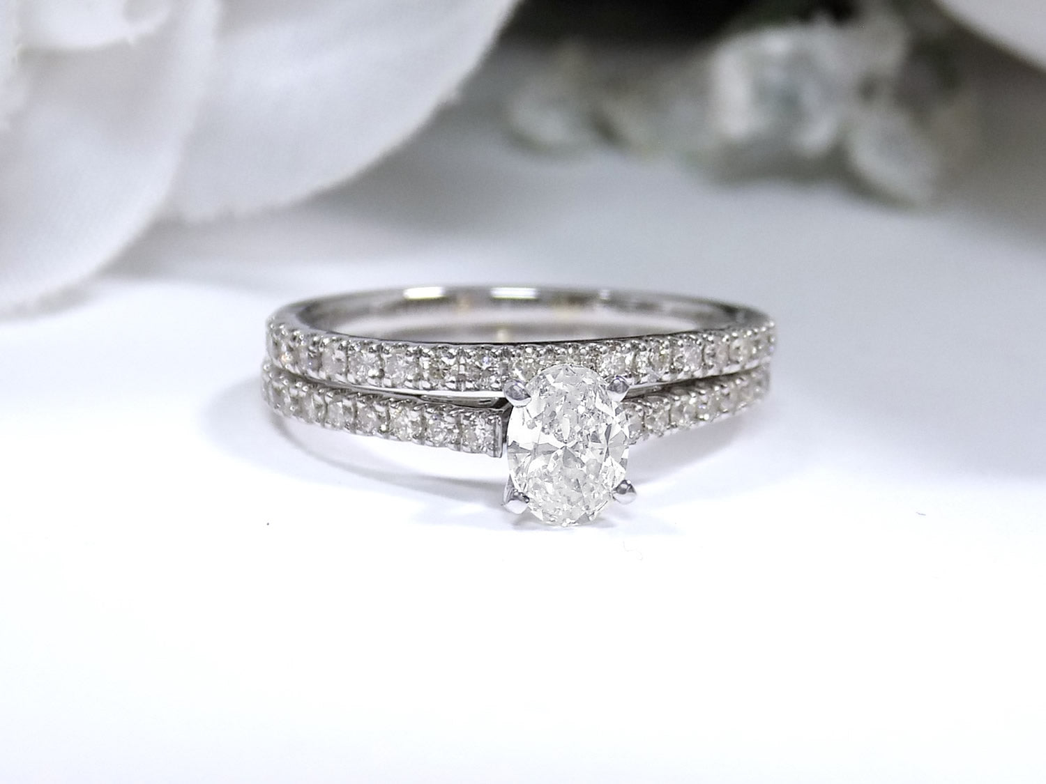 This is a natural 1ct total weight oval shape diamond bridal set with engagement ring and matching band in white gold with a white background.