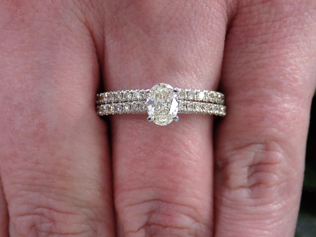 This is a natural oval shape diamond wedding set ring with matching band in white gold shown on a woman's finger.