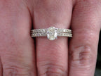 This is a natural oval shape diamond wedding set ring with matching band in white gold shown on a woman's finger.