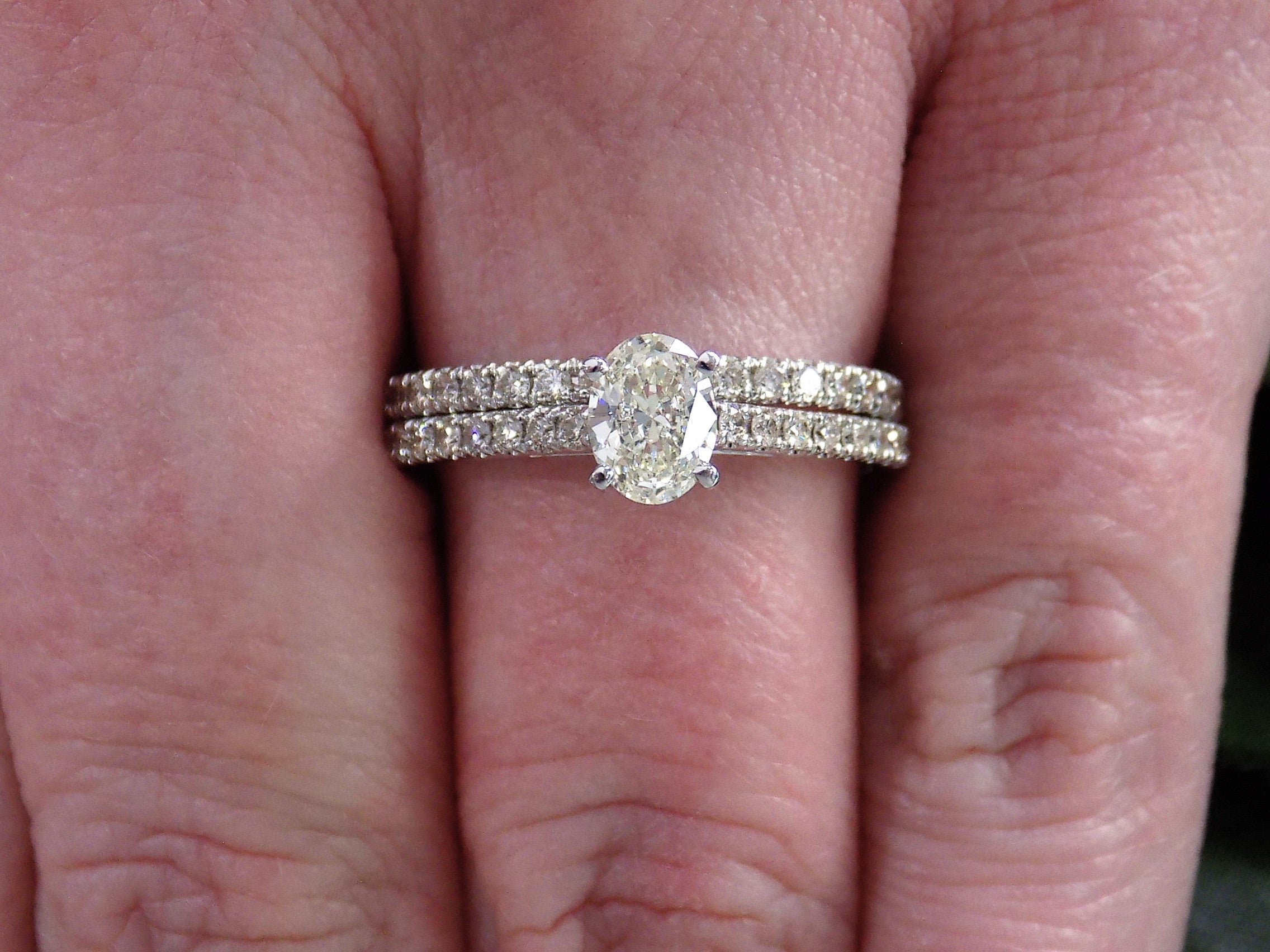 This is a natural oval shape diamond wedding set ring with matching band in white gold shown on a woman's finger.