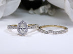 This is 2-piece natural oval shape diamond wedding set weighing 1ct total with both the engagement ring and matching band in yellow gold with white gold prongs laying side by side and a white background.