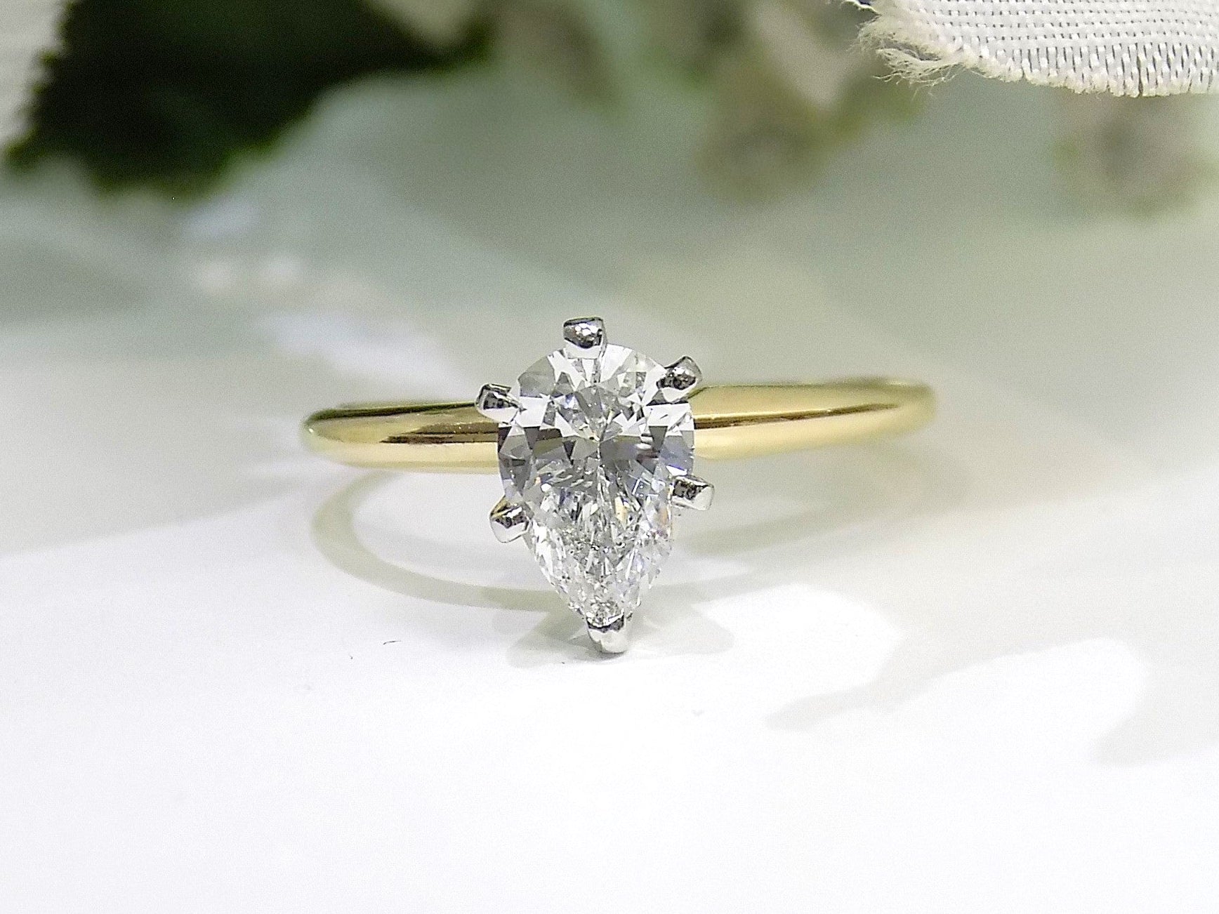 This is high quality 1.00ct natural pear shape diamond solitaire ring in yellow gold with a white background.