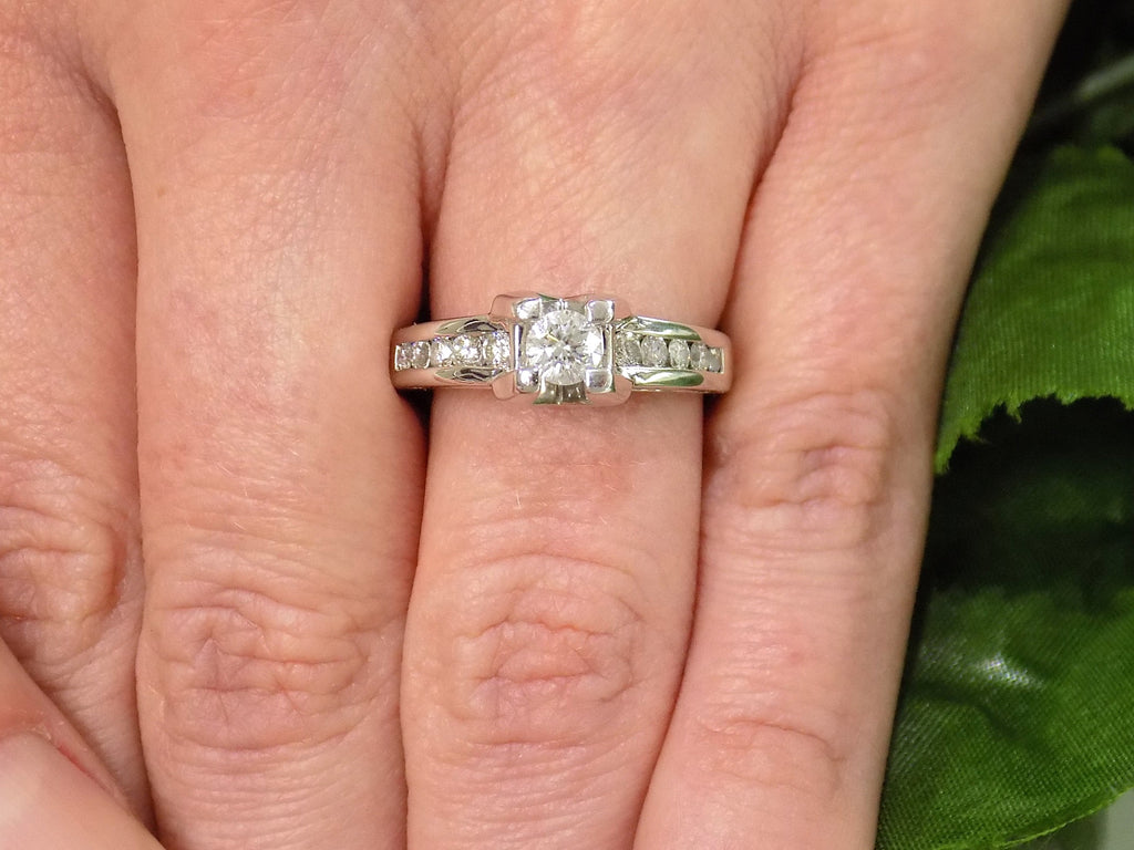 This is a 1ct total weight natural round diamond ring in white gold shown on a woman's finger.