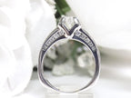 This is side view of a 1ct total weight natural round diamond ring in white gold with a white background.
