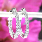 This is 2.00ct total weight natural round brilliant diamond earrings 1" in diameter inside out style earrings in 14K white gold on a white bar with pink floral background.
