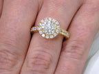 This is halo style 2.17ct total weight natural round diamond ring with a 1.52ct center diamond in yellow gold shown on a ladies' finger.