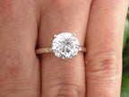 This is a natural 2.51ct round brilliant diamond solitaire in white gold shown on a woman's finger.