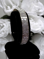 This is a 22.00ct natural princess cut diamond bracelet with 76.4 grams of 18K yellow gold on black stand with a white floral background.
