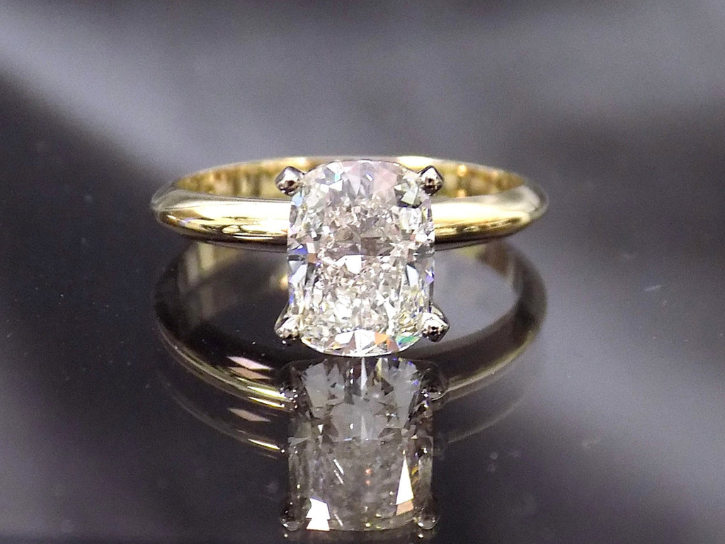 This is a 2.01ct natural elongated cushion cut diamond solitaire in yellow gold with a grayish mirrored background.