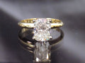 This is a 2.01ct natural elongated cushion cut diamond solitaire in yellow gold with a grayish mirrored background.