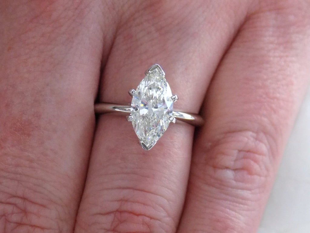 This is a 2.03ct marquise shape diamond solitaire in white gold shown on a woman's finger.