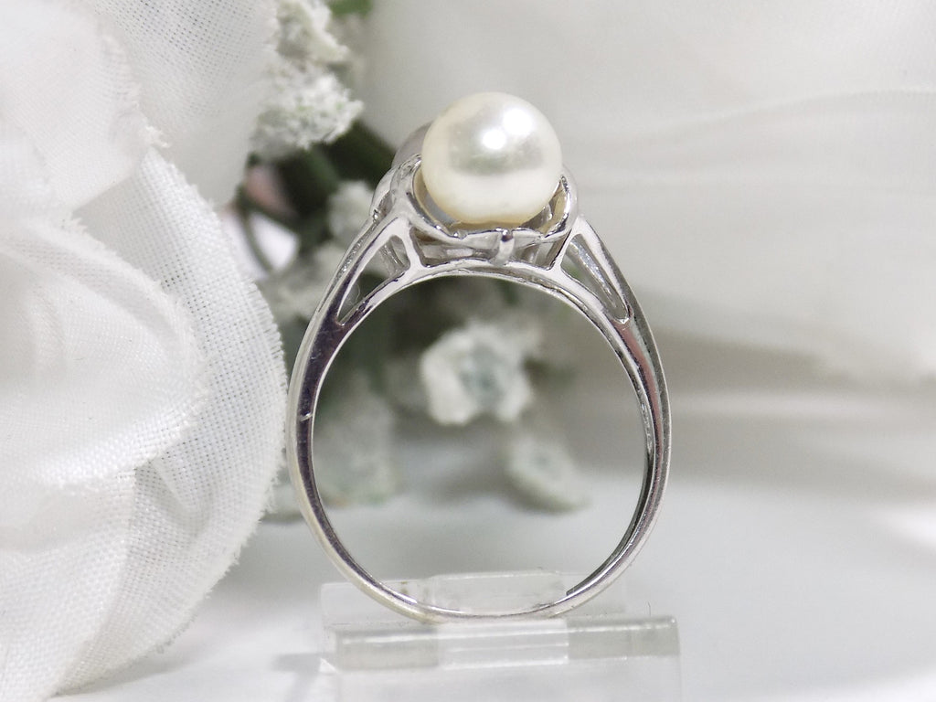 This is a side view of a fully restored like new 2-pearl ring one gray and one white pearl with diamond accents with a white background.