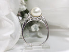 This is a side view of a fully restored like new 2-pearl ring one gray and one white pearl with diamond accents with a white background.
