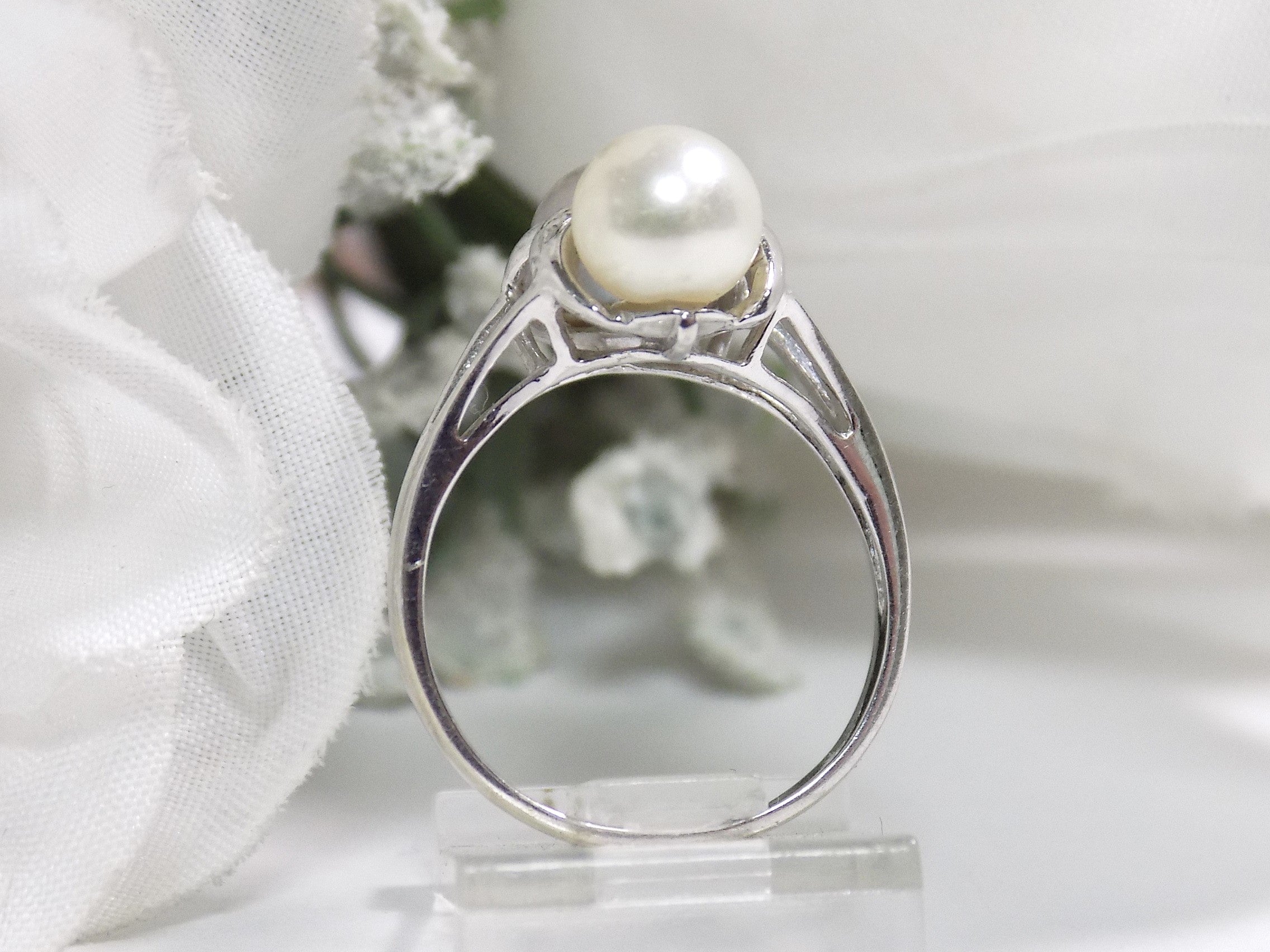 This is a side view of a fully restored like new 2-pearl ring one gray and one white pearl with diamond accents with a white background.