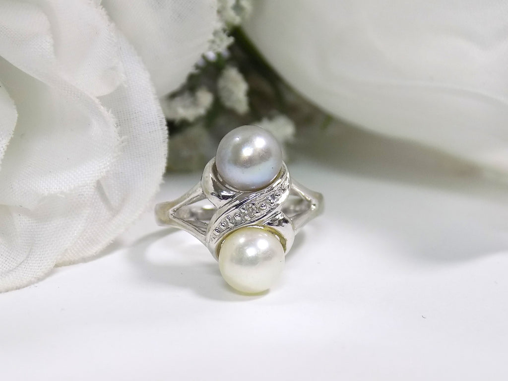 This is fully restored like new 2-pearl ring one gray and one white pearl with diamond accents shown on a white background.